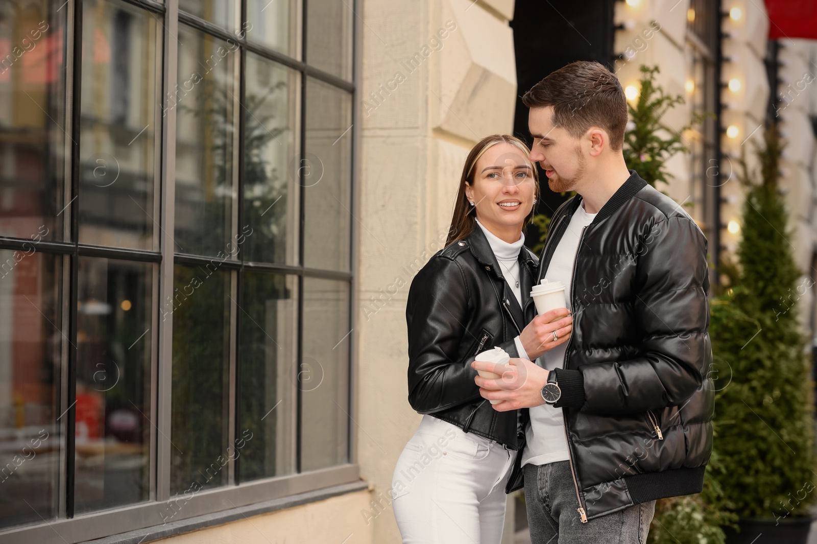 Photo of Lovely young couple with cups of coffee enjoying time together outdoors. Romantic date