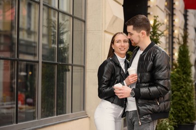 Photo of Lovely young couple with cups of coffee enjoying time together outdoors. Romantic date