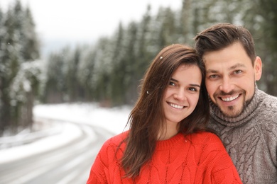 Cute couple outdoors on snowy day, space for text. Winter vacation