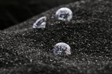 Photo of Beautiful shiny diamonds on decorative black sand