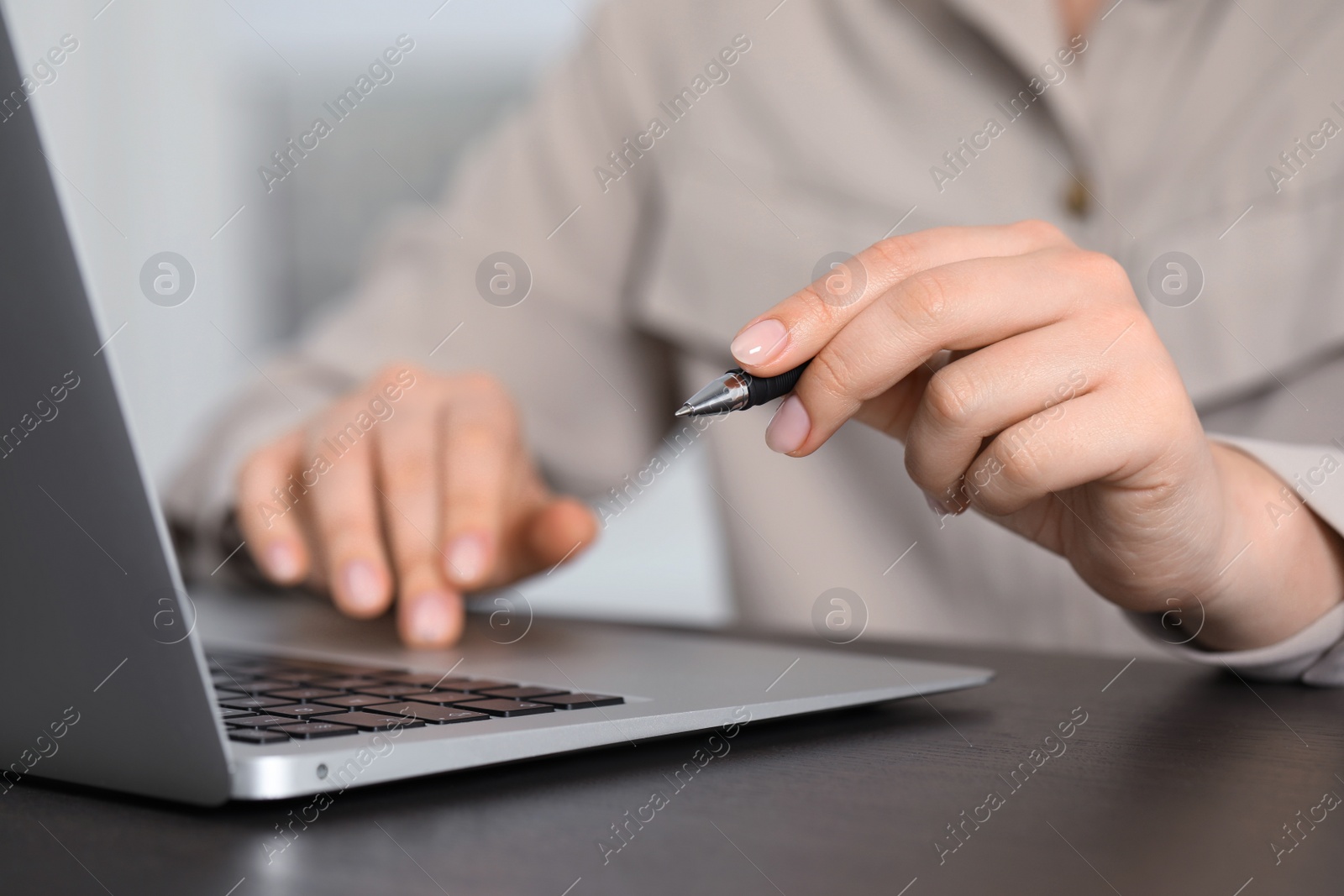 Photo of Woman with pen working on laptop, closeup. Electronic document management