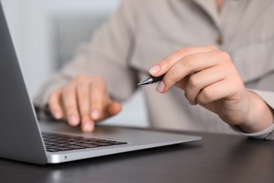 Woman with pen working on laptop, closeup. Electronic document management