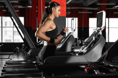 Photo of Young woman working out on treadmill in modern gym
