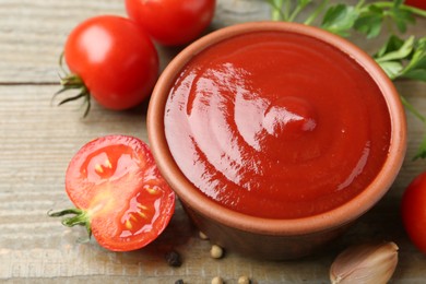 Tasty ketchup, fresh tomatoes, parsley and spices on wooden table, closeup