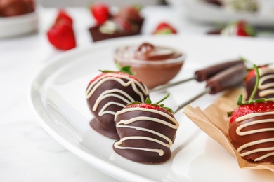 Photo of Plate with chocolate covered strawberries on table, closeup