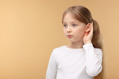 Photo of Little girl with hearing problem on pale brown background. Space for text