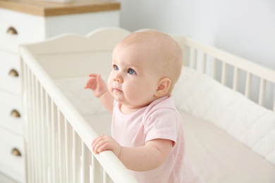 Photo of Cute baby girl in crib at home. Bedtime schedule