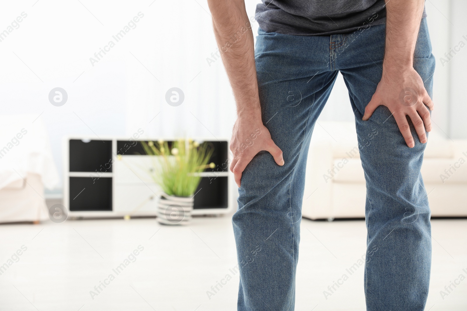 Photo of Young man suffering from leg pain indoors, closeup. Space for text