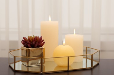 Photo of Burning candles and succulent on table indoors