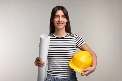 Architect with hard hat and draft on light grey background