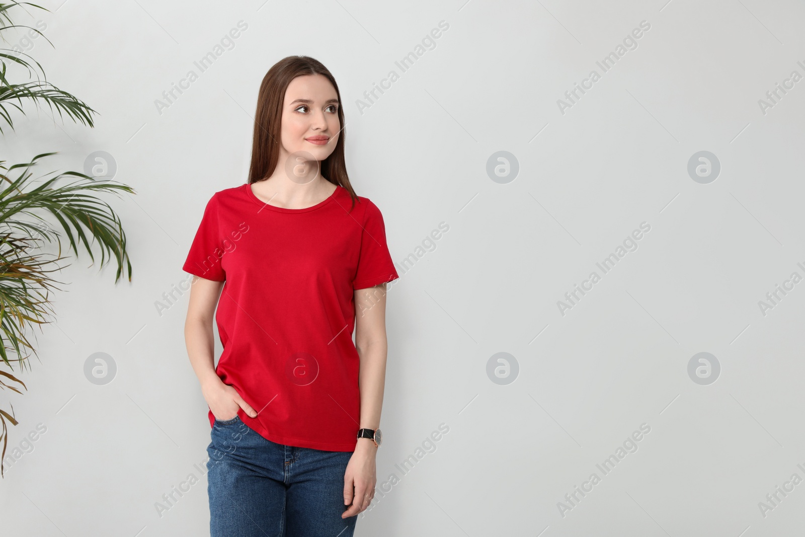 Photo of Young woman in t-shirt near light wall. Mock up for design