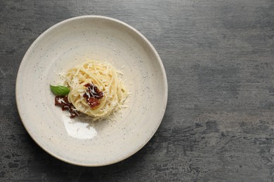 Photo of Tasty spaghetti with sun-dried tomatoes and cheese on grey table, top view and space for text. Exquisite presentation of pasta dish