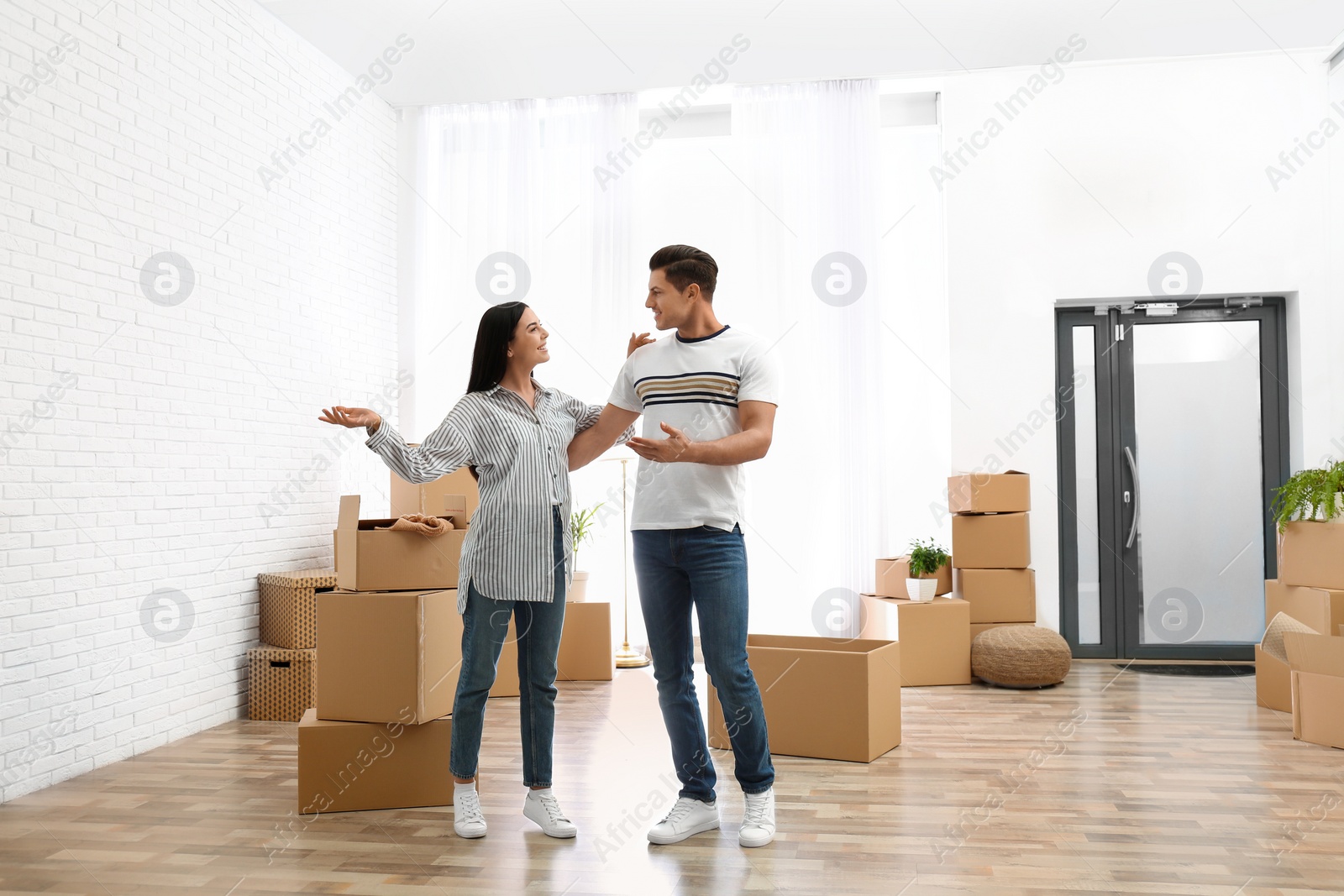 Photo of Happy couple in room with cardboard boxes on moving day