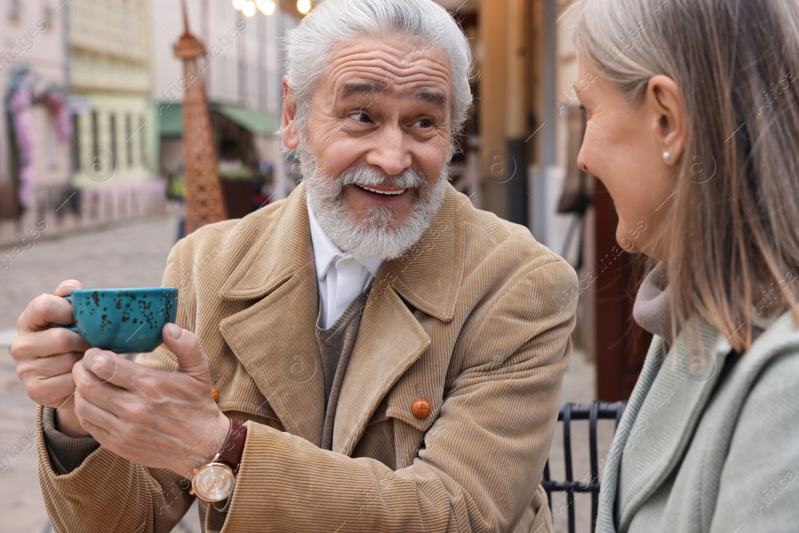 Photo of Portrait of affectionate senior couple drinking coffee in outdoor cafe