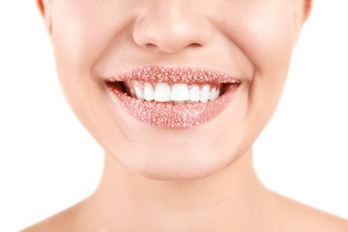 Photo of Young woman with sugar scrub on lips against white background, closeup