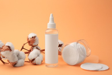 Photo of Composition with makeup remover and cotton flowers on pale orange background