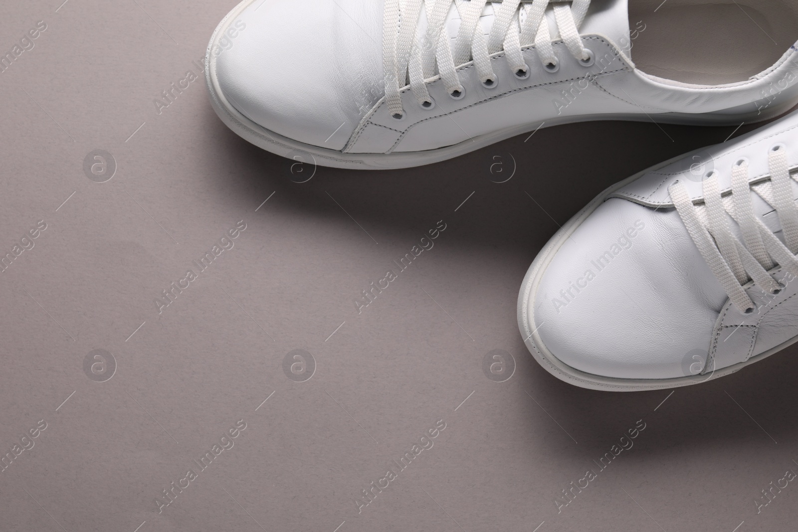 Photo of Pair of stylish white sneakers on grey background, top view. Space for text