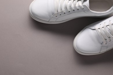 Pair of stylish white sneakers on grey background, top view. Space for text