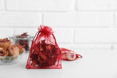 Photo of Scented sachet with dried hibiscus flowers on white table, space for text