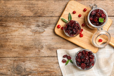 Flat lay composition with tasty fresh and dried cranberries on wooden table. Space for text