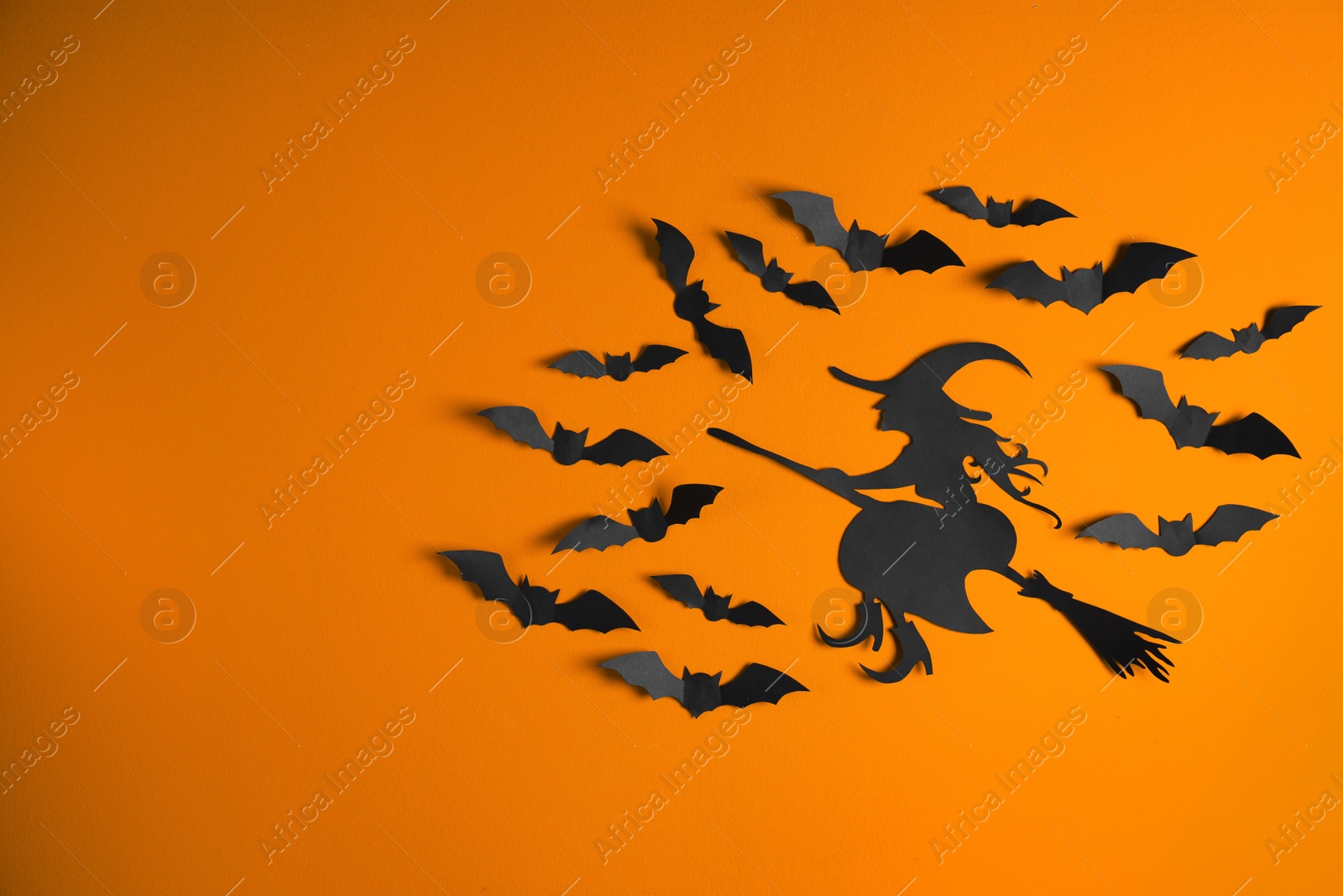 Photo of Paper bats and witch cutout on color background with space for text. Halloween decor