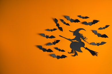 Paper bats and witch cutout on color background with space for text. Halloween decor