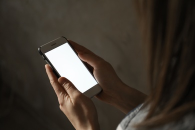 Woman using smartphone in dark room, closeup with space for text. Loneliness concept