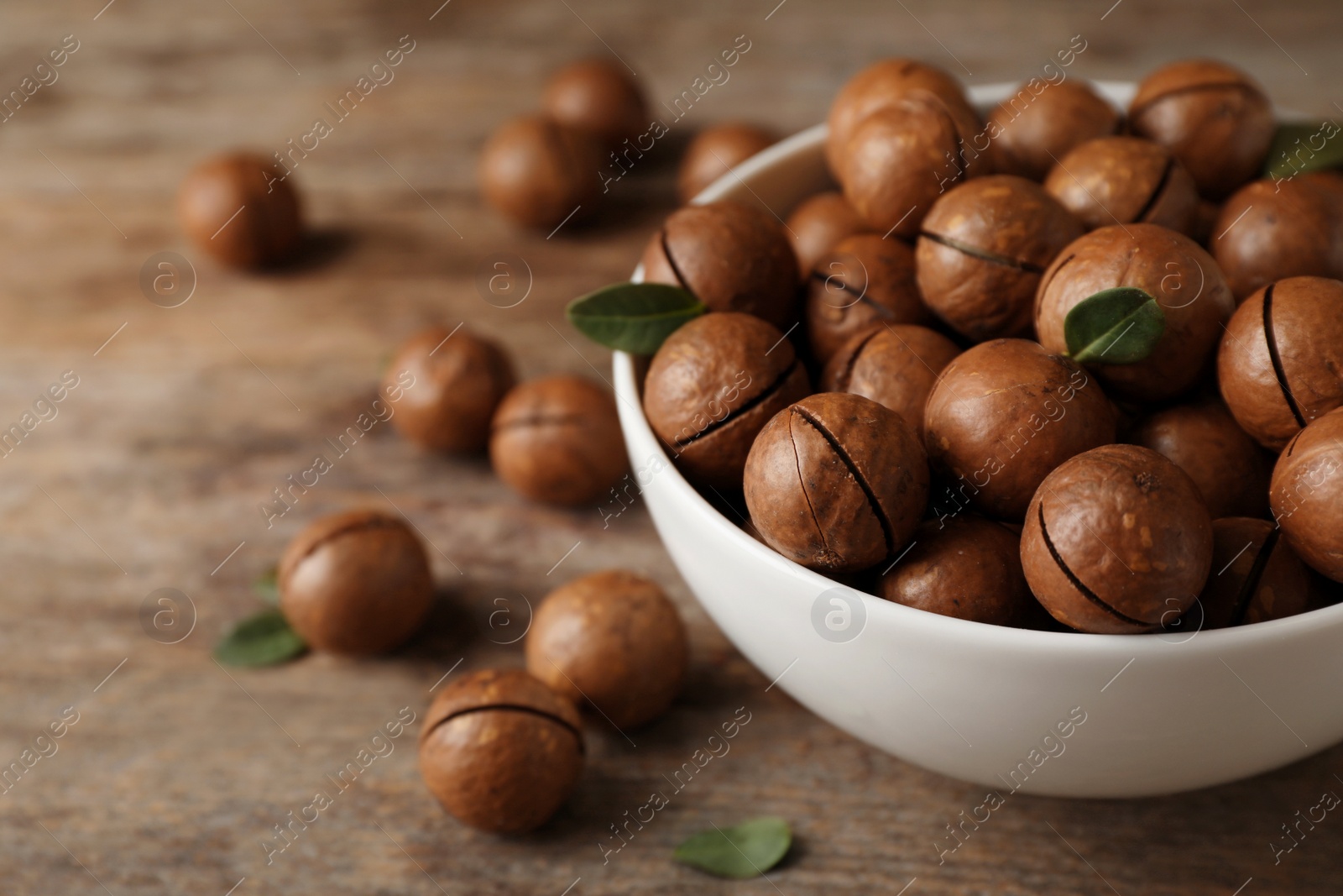 Photo of Bowl with organic Macadamia nuts and space for text on wooden background