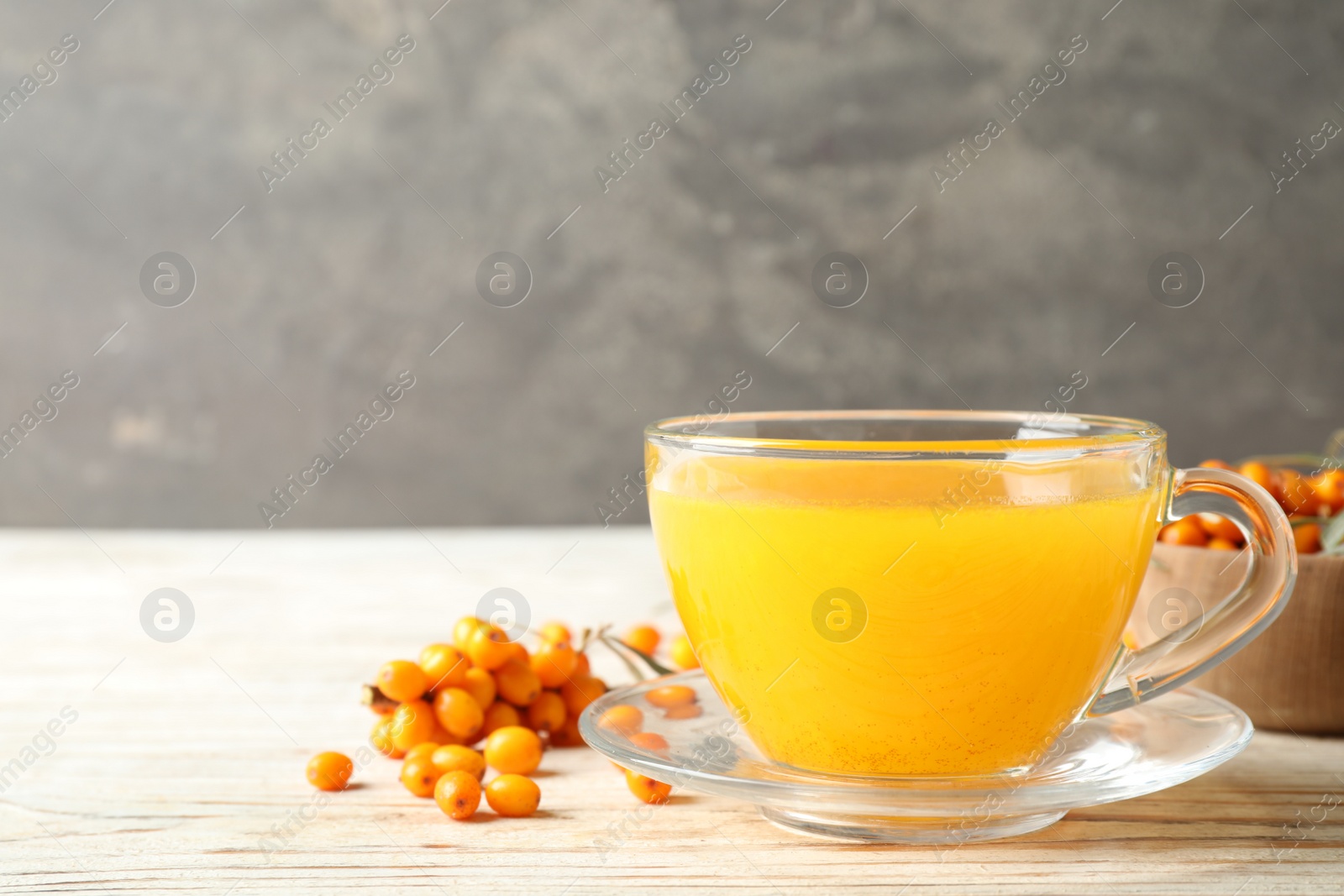 Photo of Fresh sea buckthorn tea on white wooden table. Space for text