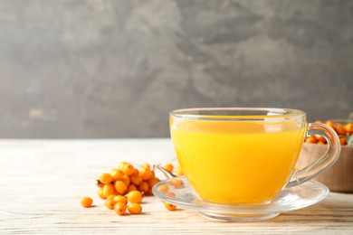 Photo of Fresh sea buckthorn tea on white wooden table. Space for text