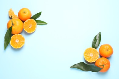Photo of Flat lay composition with fresh ripe tangerines and leaves on light blue background, space for text. Citrus fruit