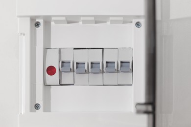 Photo of Open fuse box on beige wall, closeup