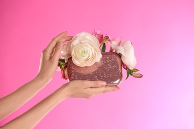 Photo of Woman holding elegant handbag with spring flowers on pink background, closeup