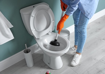 Photo of Woman cleaning toilet bowl in bathroom