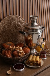 Photo of Traditional Russian samovar with treats on wooden table