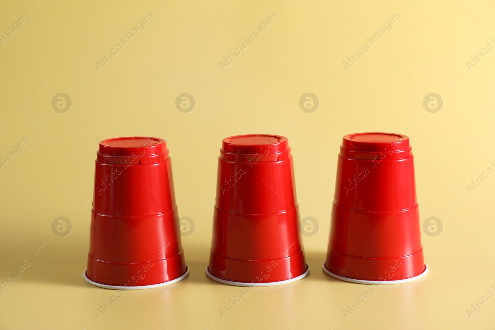 Photo of Shell game. Three red cups on yellow background
