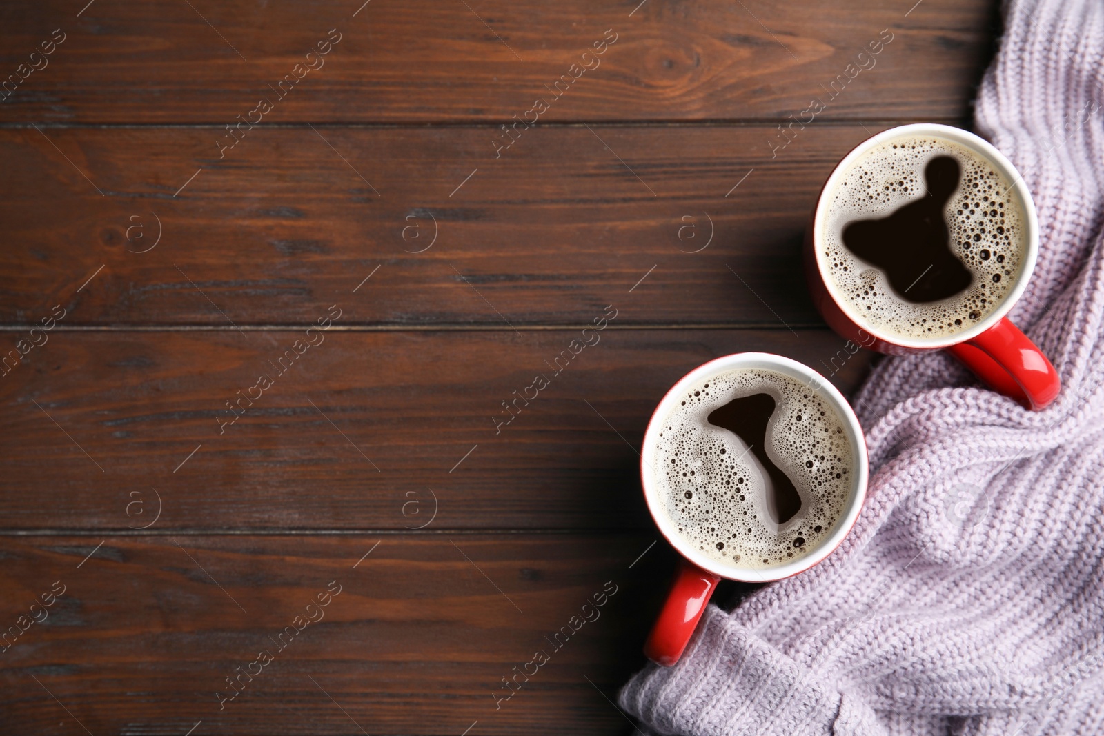 Photo of Flat lay composition cups of hot coffee and knitted sweater on wooden background, space for text. Winter drink