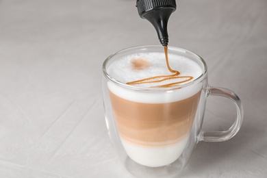 Adding caramel topping to latte macchiato on table