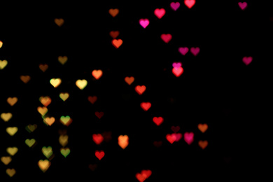 Blurred view of heart shaped lights on black background. Bokeh effect