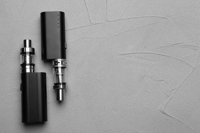 Photo of Electronic cigarettes on grey table, flat lay with space for text. Smoking alternative