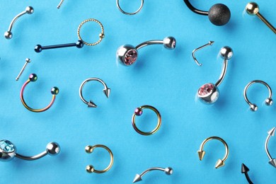 Photo of Stylish piercing jewelry on light blue background, flat lay