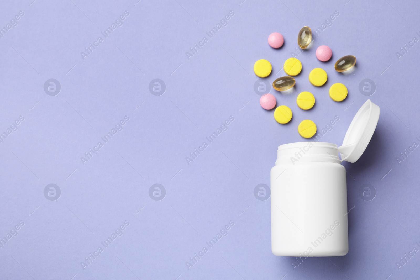 Photo of White bottle and different vitamin pills on violet background, top view. Space for text