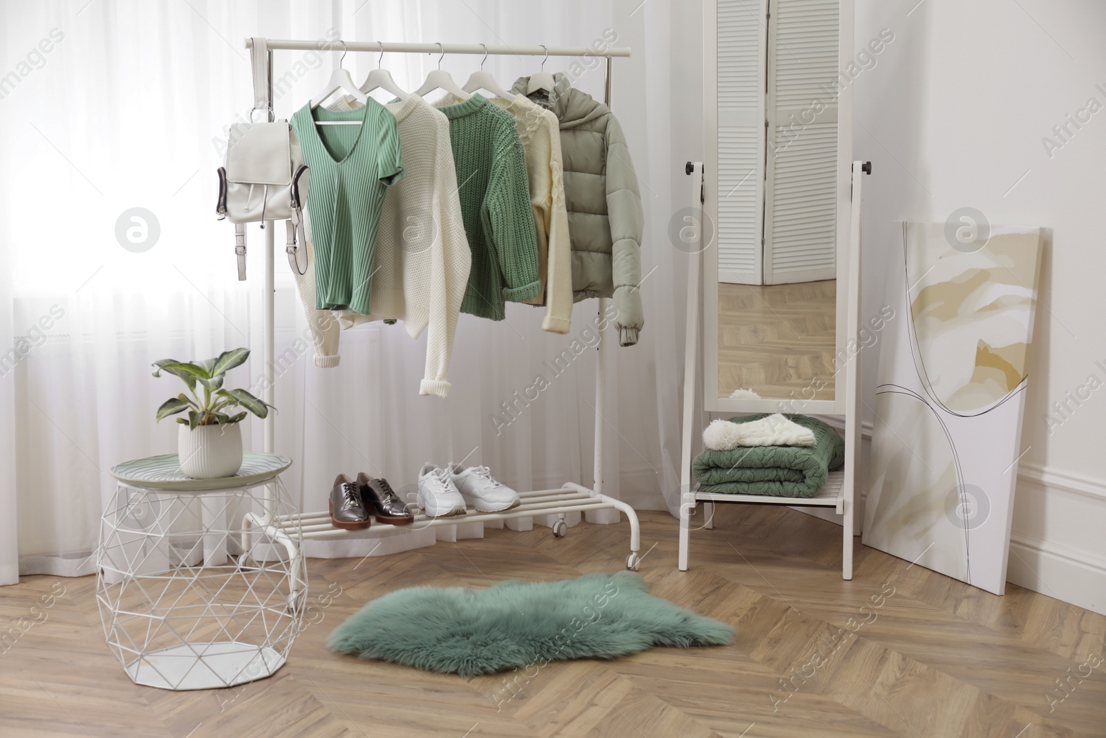 Photo of Rack with stylish warm clothes and shoes near mirror in dressing room