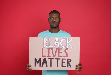 African American man holding sign with phrase Black Lives Matter on red background. End racism