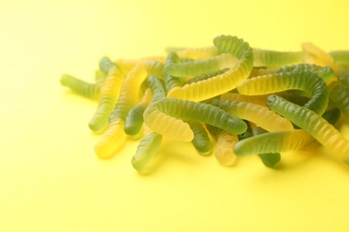 Photo of Pile of colorful jelly worms on yellow background