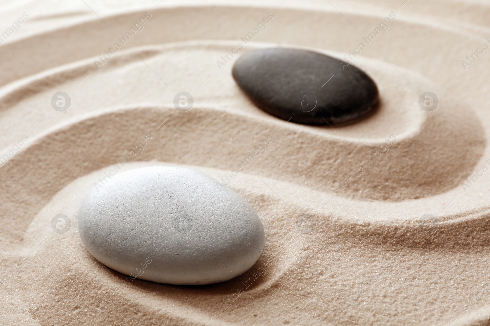 Photo of Zen garden stones on sand with pattern. Meditation and harmony