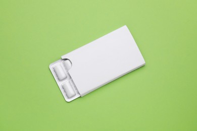 Photo of Blister with chewing gums on pale green background, top view