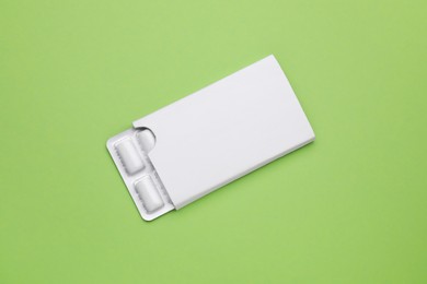 Blister with chewing gums on pale green background, top view