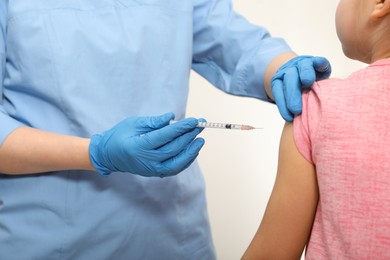 Doctor giving injection to little girl in hospital, closeup. Immunization concept