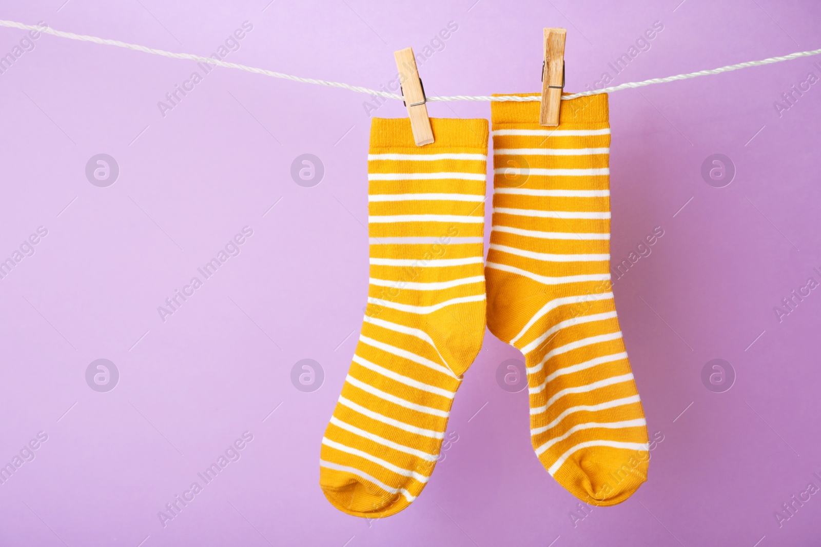 Photo of Cute child socks on laundry line against color background. Space for text